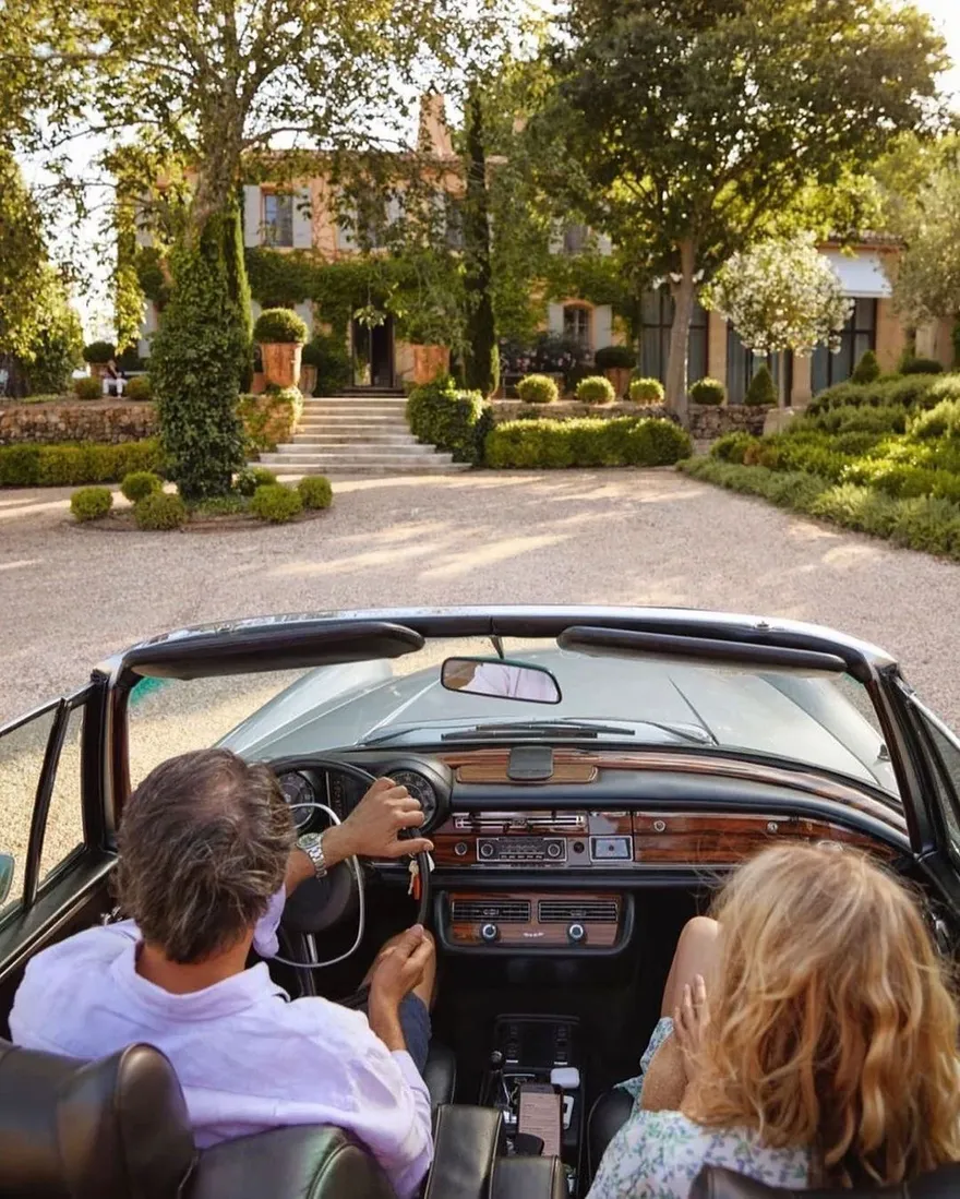 Paar im offenen Oldtimer-Cabrio bei der Ankunft vor einer Villa